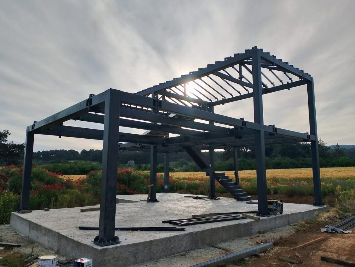 Steel frame erected on a concrete slab in a field at sunset